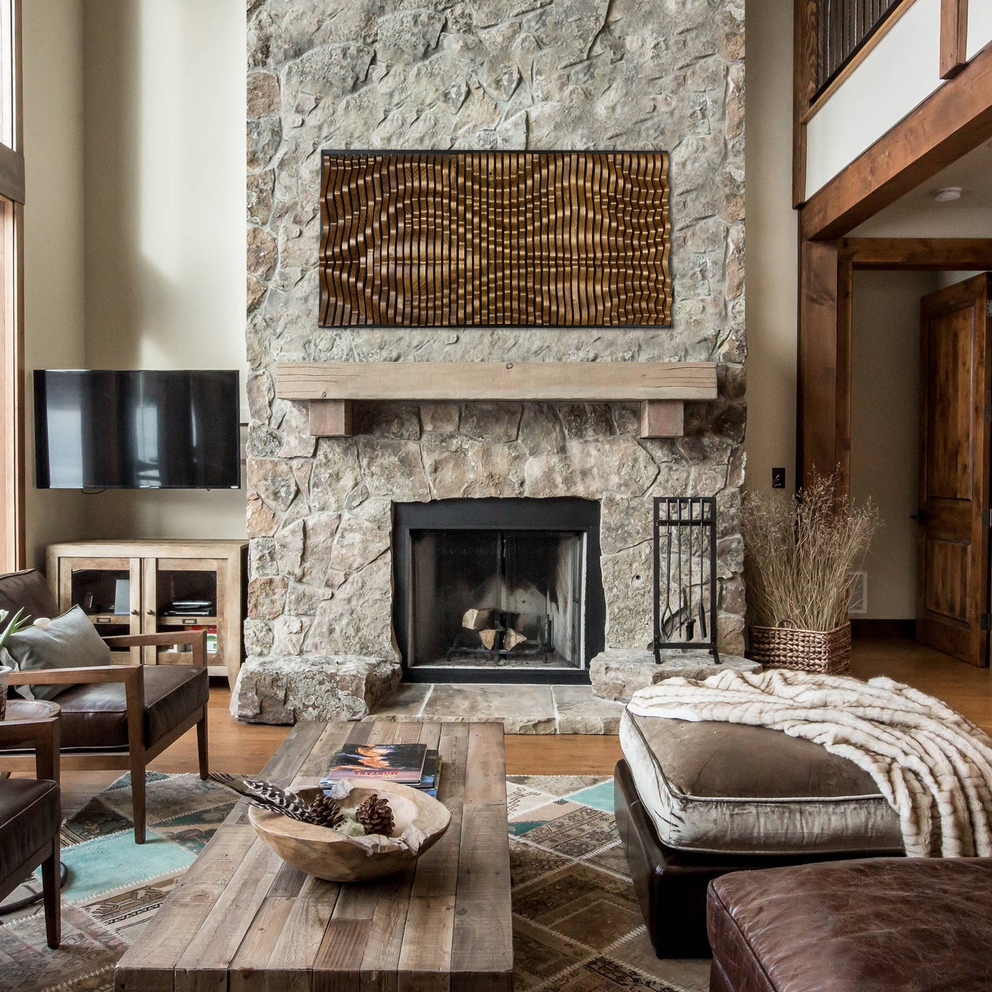 GOLIATHUS Solid Wood Acoustic Wall Art Panel installed above a rustic stone fireplace in a cozy cabin-style living room setting.